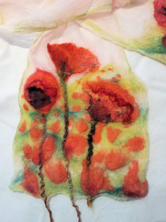 Closeup of one end of poppy scarf showing poppy field. Merino, tissue silk, silk noile, variegated yarn.